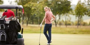 Female golfer on tee box next to golf cart